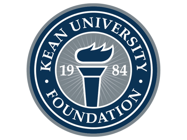 Circular seal of Kean University Foundation featuring a stylized torch in the center with “1984” split on either side, surrounded by a blue ring with the foundation name in white text.