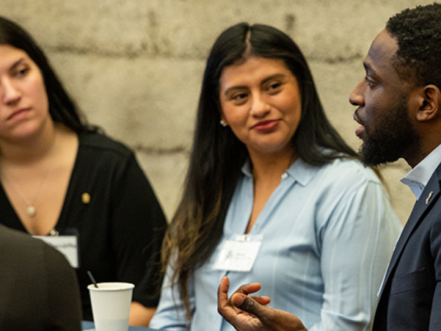 Three alumni (2 female, one male) sitting at a table engaging at a networking event