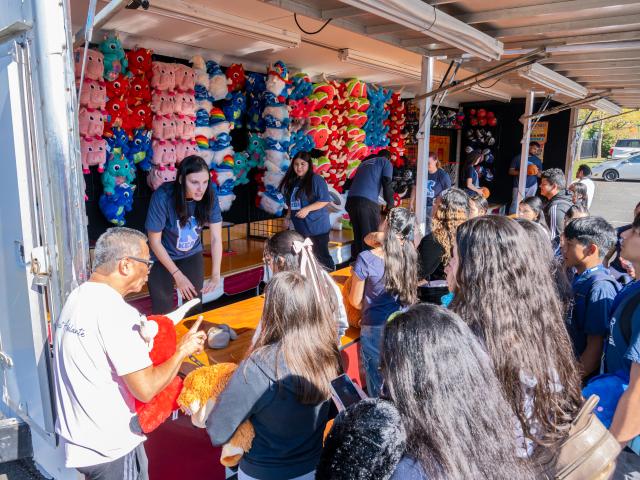 People waiting to participate at Homecoming carnival booth with stuffed animals hanging 
