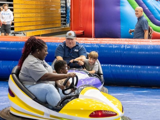Kean parents and children drive bumper cars at Kean's Homecoming carnival